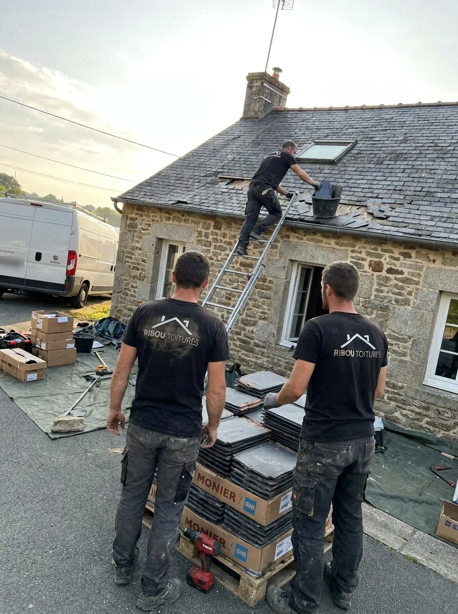 Couvreurs de Ribou Toitures remplaçant des ardoises sur une maison en pierre près de Cholet, échelle contre le toit et palette de matériaux